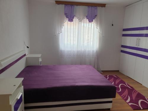 a bedroom with a purple bed and a window at Villa Big Mama in Živinice