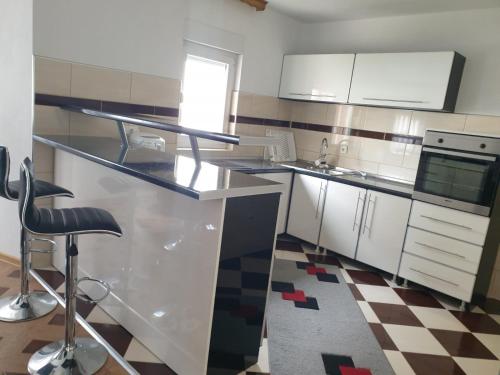 a kitchen with a counter with a sink and a stool at Villa Big Mama in Živinice