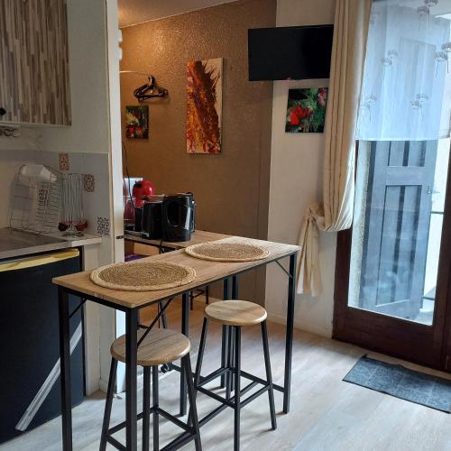 une cuisine avec une table et des tabourets dans une pièce dans l'établissement Studio SAFARI, à Luchon