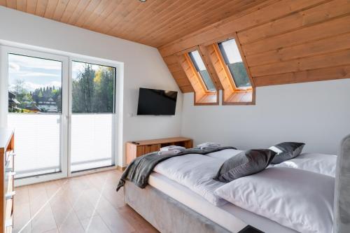 a bedroom with a bed and a tv and windows at Villach in Bukowina Tatrzańska