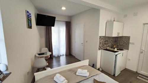a bedroom with a bed and a kitchen with a sink at Apartmani TOKI in Mrkonjić Grad