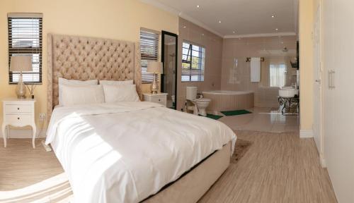 a bedroom with a large white bed and a bathroom at Lovely and Peaceful 3 bedroom house in Cape Town