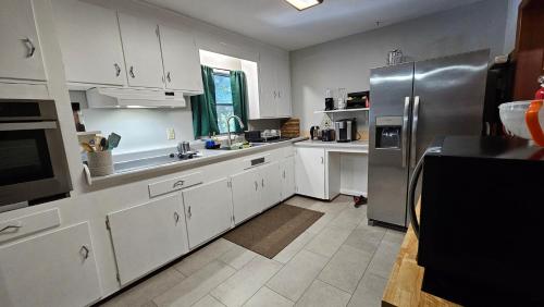 a kitchen with white cabinets and a stainless steel refrigerator at Charlotte's House in Jacksonville