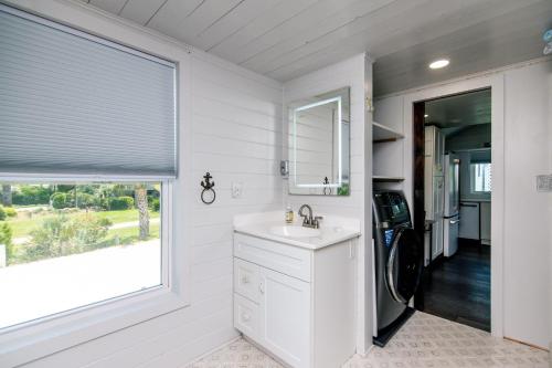 Una cocina blanca con fregadero y ventana. en Marysol Cottage, en Edisto Beach