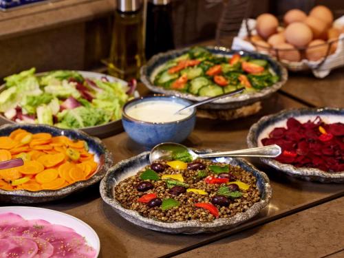 a table topped with bowls of food and bowls of vegetables at Cures Marines Hotel Thalasso & Spa Trouville - MGallery Collection in Trouville-sur-Mer