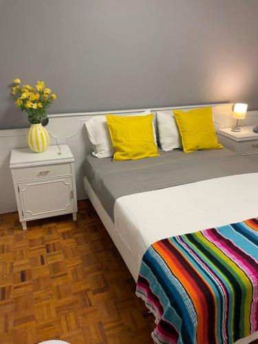 a bed with yellow pillows and a vase of flowers on it at Mexicaníssima 4BR, 4 to 11 guests in Coyoacán in Mexico City