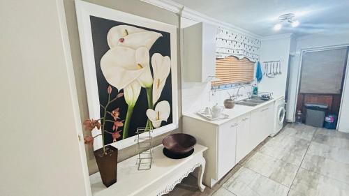 une cuisine avec un tableau de fleur au mur dans l'établissement Artzys Cottage 1km to Olivedale Clinic, à Northriding