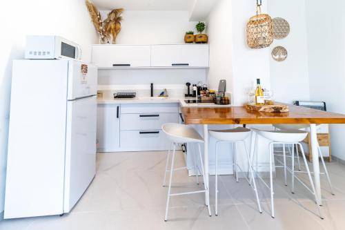 een keuken met witte kasten en een houten tafel met krukken bij LOMA in Hagoshrim