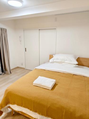 a bedroom with a large bed with a yellow blanket at THE ONE kouennji in Tokyo