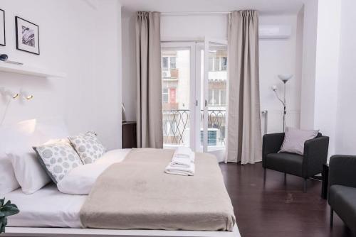 a white bedroom with a large bed and a chair at Extra Central NEW home with AC in Budapest