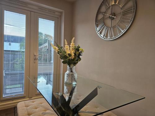 un vase de fleurs sur une table en verre avec une horloge dans l'établissement Spacious 3-Storey Home from Home in Hetton le Hole, à Hetton le Hole