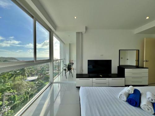a bedroom with a bed and a large window at Sunset Plaza by RESAVA in Karon Beach