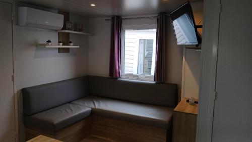 ミミザン・プラージュにあるCAMPING 4 etoiles 3 Chambresのソファと窓のある小さな部屋