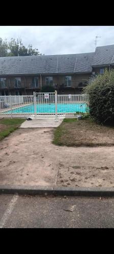 une clôture blanche en face d'un bâtiment avec piscine dans l'établissement L,orchidée, à Équemauville