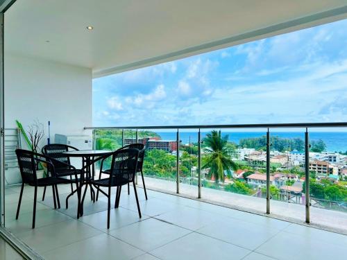 a balcony with a table and chairs and a view of the ocean at Sunset Plaza by RESAVA in Karon Beach