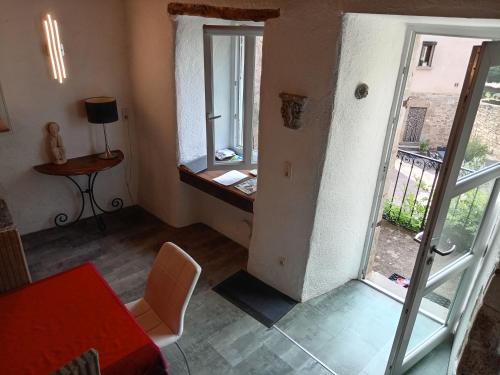 sala de estar con mesa y puerta a un balcón en Maison de caractère au cœur des grands causses, en Viala-du-Tarn