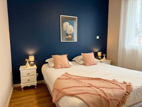 a bedroom with a blue wall and a bed at L'Abalone 3 Étoiles in Aizenay