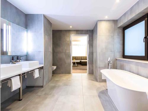 a bathroom with two sinks and a tub and a window at Novotel Wrocław Centrum in Wrocław