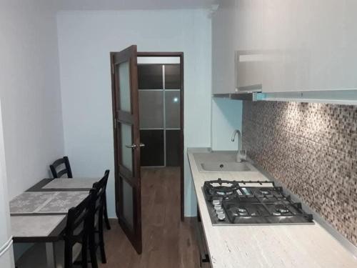 a kitchen with a stove and a table and a counter at Apartament Decebal- 2 dormitoare in Bistriţa
