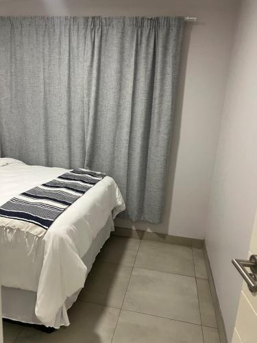 Un dormitorio con una cama y una ventana con cortinas. en Modern Apartment in Centurion, en Centurion