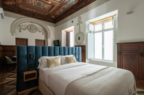 a bedroom with a large bed with a blue headboard at Apartamentos Gravina 31 in Seville