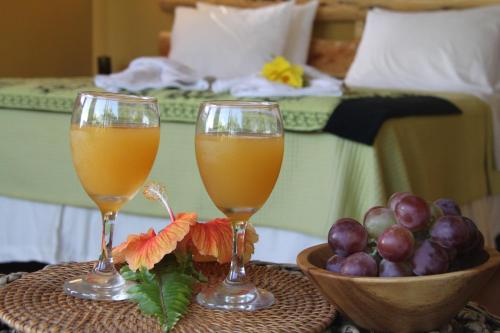 dos vasos de zumo de naranja y fruta en una mesa en una habitación de hotel en Hotel Uka Mana, en Hanga Roa