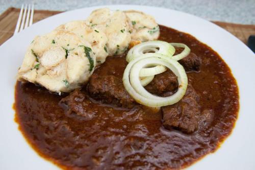 a white plate of food with meat and sauce at Pension Herman in Rudník