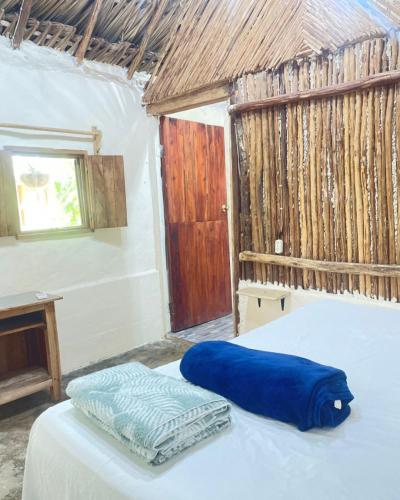 a bedroom with a bed with blue sheets and a window at Aldea Muul Tuunich in Bacalar