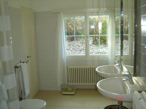 une salle de bain blanche avec deux lavabos et une fenêtre dans l'établissement Large Home in Country near Zurich, à Othmarsingen