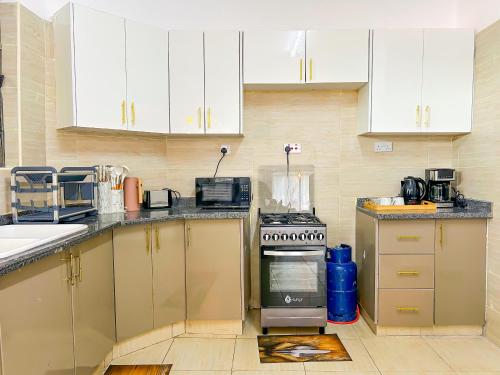 eine Küche mit weißen Schränken und einem Herd mit Backofen in der Unterkunft Majestic Apex Residence in Bamburi