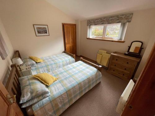 een slaapkamer met twee bedden, een ladekast en een raam bij Hopeman Cottage in Hopeman