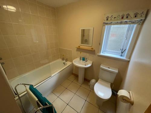 een badkamer met een wastafel, een toilet en een ligbad bij Hopeman Cottage in Hopeman