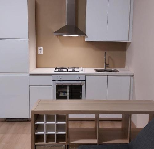 a kitchen with white cabinets and a wooden table at La Gatta sui Tetti in Osimo