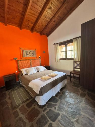 a bedroom with orange walls and a large bed at Cabañas Balcones de Tafi in Tafí del Valle