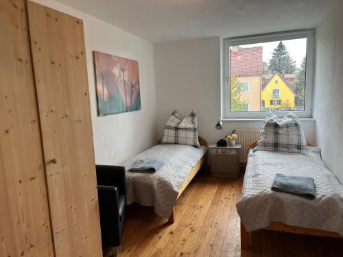 a small bedroom with two beds and a window at Ferienwohnung in Landsberg am Lech in Landsberg am Lech