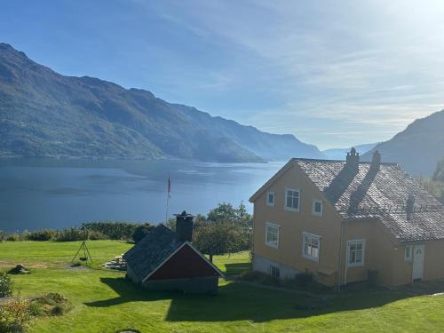 una casa en un campo con un lago y montañas en Jåstad Gjestetun, en Jåstad