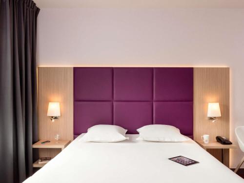a bedroom with a large bed with a purple headboard at Aparthotel Adagio Paris Malakoff Chatillon in Malakoff