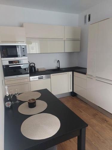 a kitchen with white cabinets and a black table at Apartament 24 Bolesławiec z garażem podziemnym in Bolesławiec