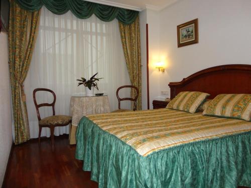 a hotel room with a bed and two chairs at Pensión Araba II in Vitoria-Gasteiz
