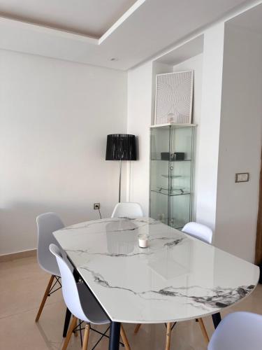 a white dining room with a white table and chairs at Appart familial avec terrasse et piscine, à 2 pas de la plage des nations - Rabat in Sidi Bouqnadel