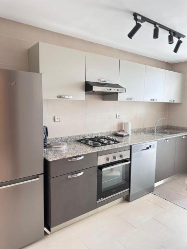 a kitchen with stainless steel appliances and white cabinets at Appart familial avec terrasse et piscine, à 2 pas de la plage des nations - Rabat in Sidi Bouqnadel