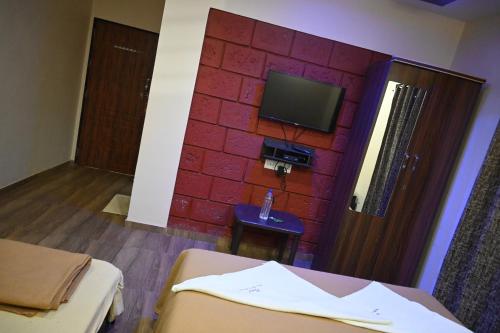 ein Zimmer mit einer roten Backsteinwand und einem Fernseher in der Unterkunft Coral Beach Resort, Diveagar in Diveagar