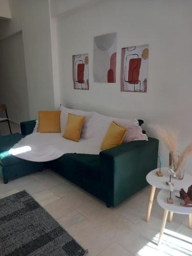 a green couch in a living room with two tables at loft ΑLEXIA in Pyrgos