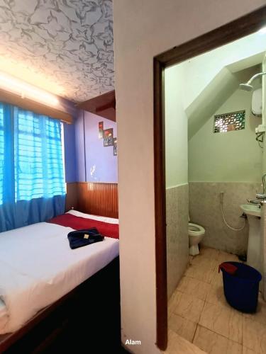 a small room with a bed and a toilet at Hotel Falcon View in Darjeeling