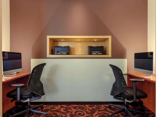 a waiting room with two chairs and two monitors at Mercure Hotel Schweinfurt Maininsel in Schweinfurt