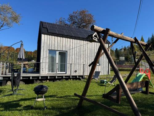 a small house with a solar roof on a yard at Domek Mecenasa in Nieledwia