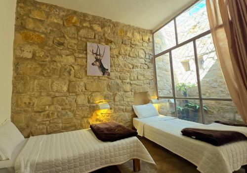 a bedroom with two beds and a stone wall at Dana Gardens Hotel in Dana