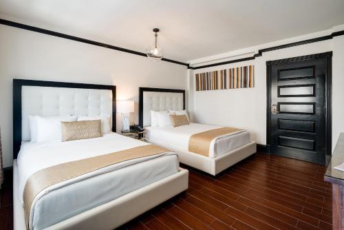 Un dormitorio con dos camas y una puerta. en Hotel Croydon, en Miami Beach