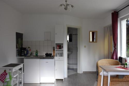 ライプツィヒにあるFerienhaus Hübnerの白いキャビネットとテーブル付きのキッチン