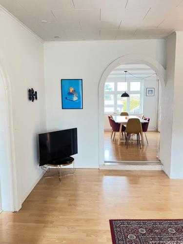 a living room with a table and a television at Spacious Apartment Near City & Åløkke Forest in Odense